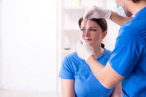 Woman consulting with a male doctor about plastic surgery, specifically discussing options for revision rhinoplasty.