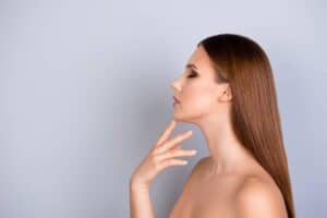 Woman showing results after neck lift surgery, highlighting tightened skin and improved neck contour.